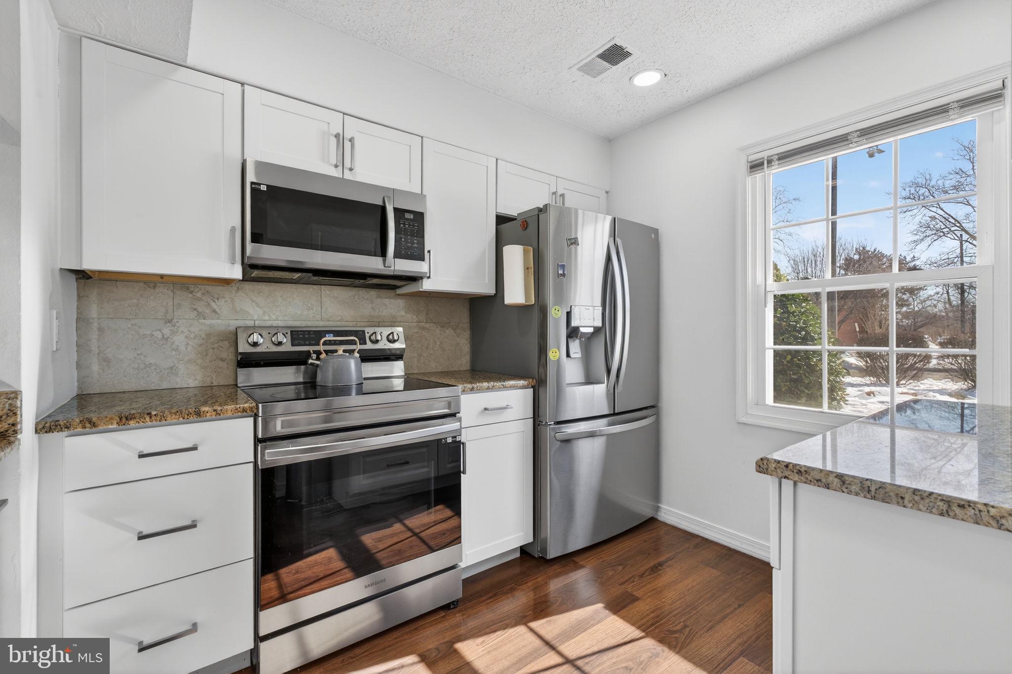 8526 Forrester Boulevard, Unit 890 Springfield, VA 22152 - Photo 6 of 24 a kitchen with stainless steel appliances white cabinets a stove a microwave and a refrigerator