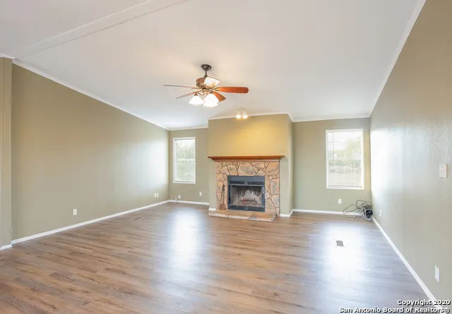 an empty room with wooden floor fireplace and window