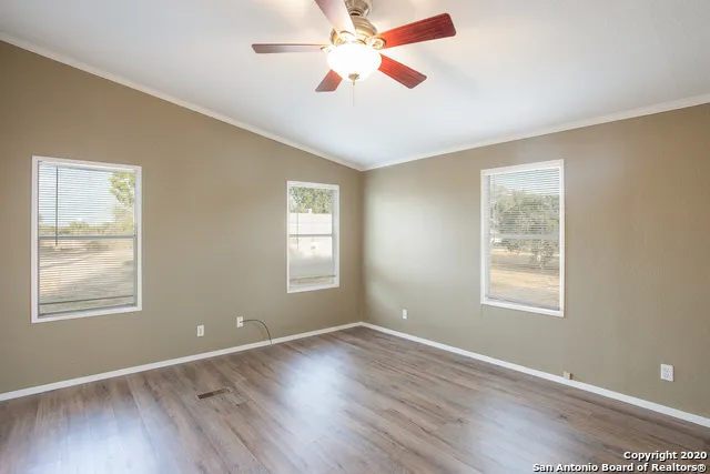 a view of an empty room with window and wooden floor