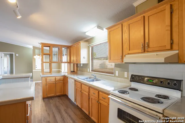 a kitchen that has a sink a stove and cabinets