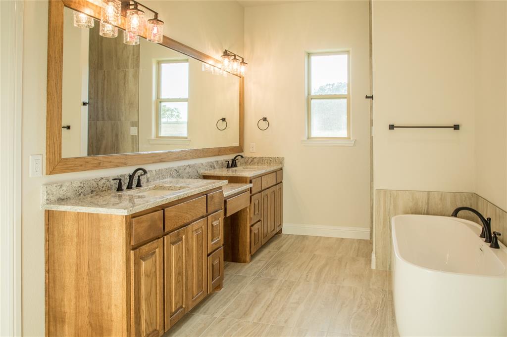 141 Prairie Winds Drive Poolville, TX 76487 - Photo 14 of 15 a bathroom with a granite countertop sink a mirror and a bathtub