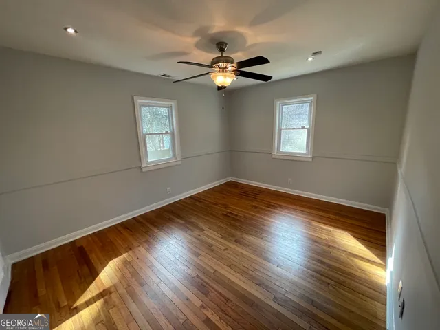 a view of empty room with wooden floor and fan