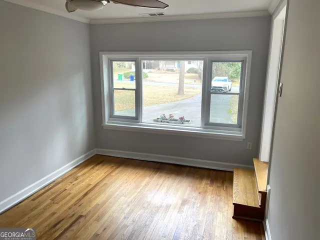 an empty room with wooden floor and windows
