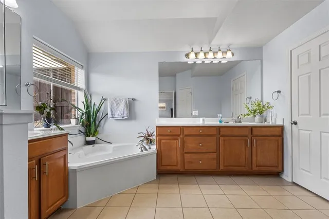 a spacious bathroom with a granite countertop sink a mirror and a bathtub