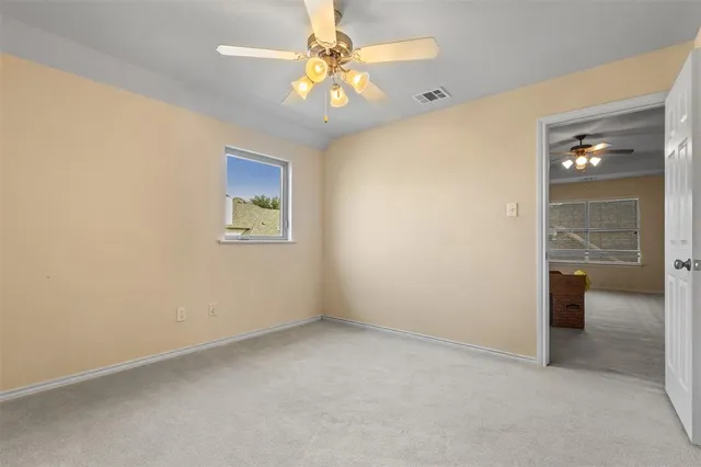 an empty room with a chandelier fan and a window