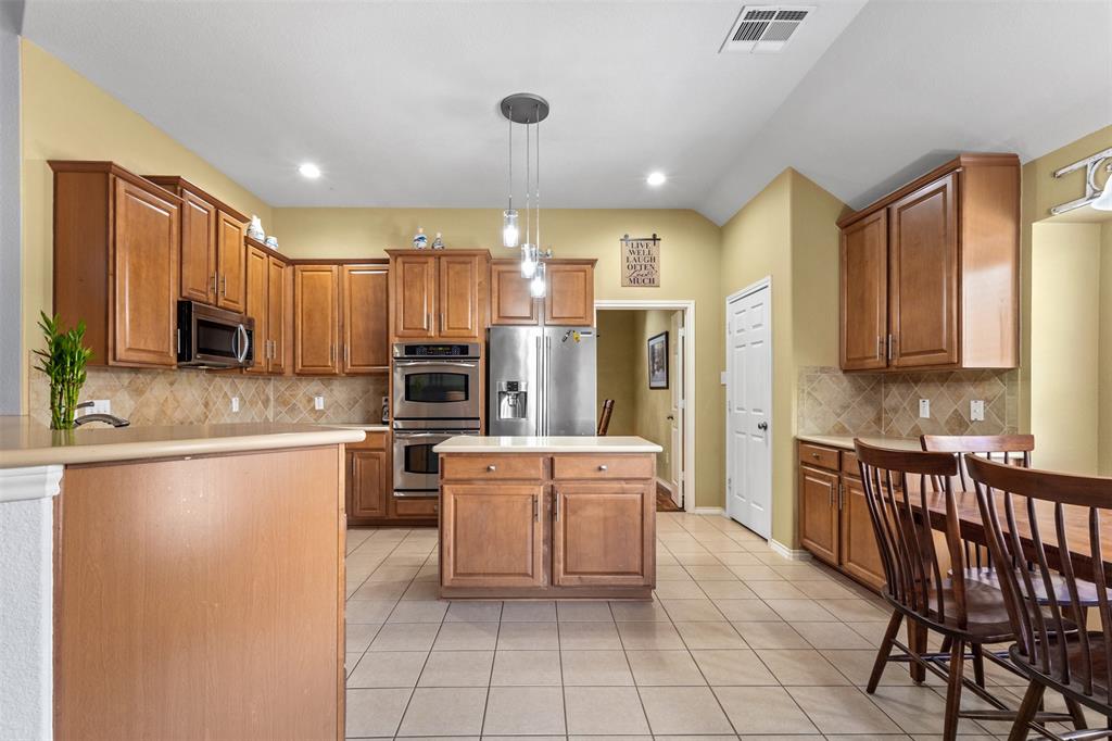 12334 Blue Ridge Drive Frisco, TX 75033 - Photo 6 of 32 a kitchen with stainless steel appliances kitchen island granite countertop a stove top oven a sink a dining table and chairs