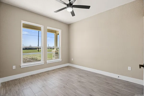 an empty room with wooden floor fan and windows