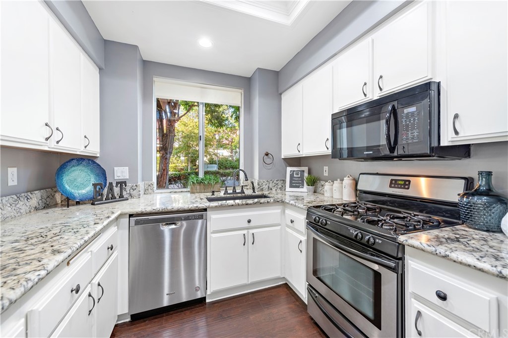 2 Vía Entrada Rancho Santa Margarita, CA 92688 - Photo 21 of 35 a kitchen with granite countertop a stove a sink and dishwasher wooden cabinets with wooden floor