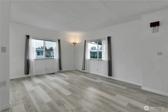 a view of an empty room with window and wooden floor