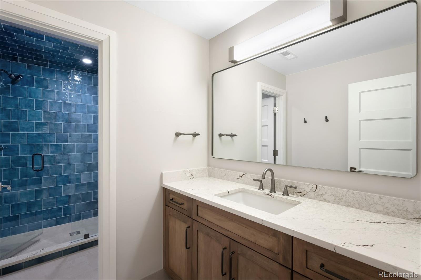 2237 South Madison Street Denver, CO 80210 - Photo 40 of 44 a bathroom with a granite countertop sink a mirror and a shower