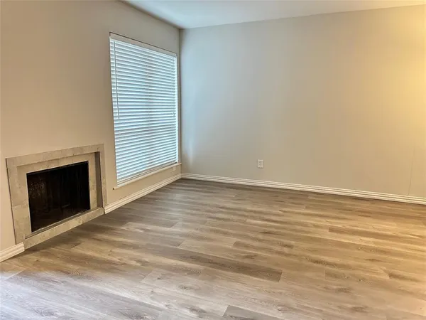 an empty room with wooden floor fireplace and windows