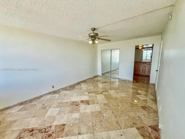 an empty room with a chandelier fan and windows