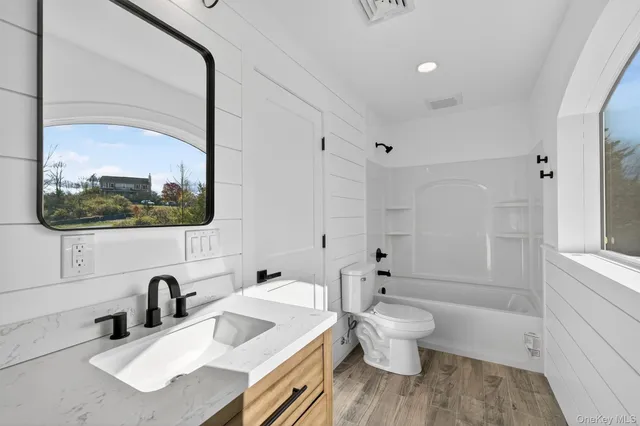 a bathroom with a sink vanity granite toilet and a mirror