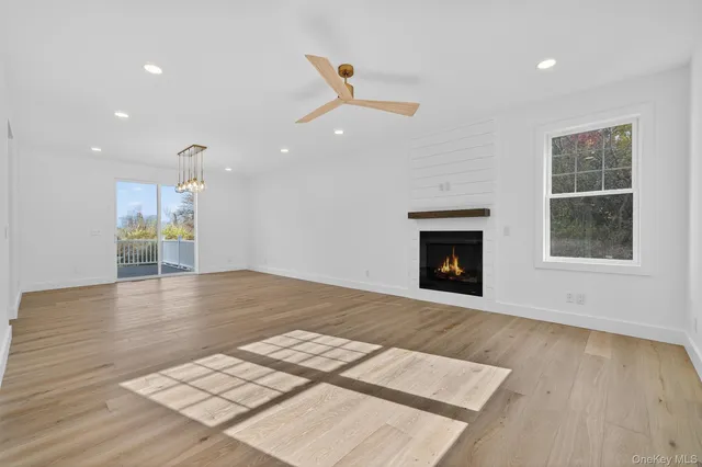 an empty room with wooden floor fireplace and windows