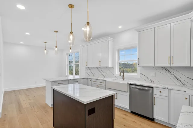 a kitchen with a sink dishwasher and white cabinets with wooden floor