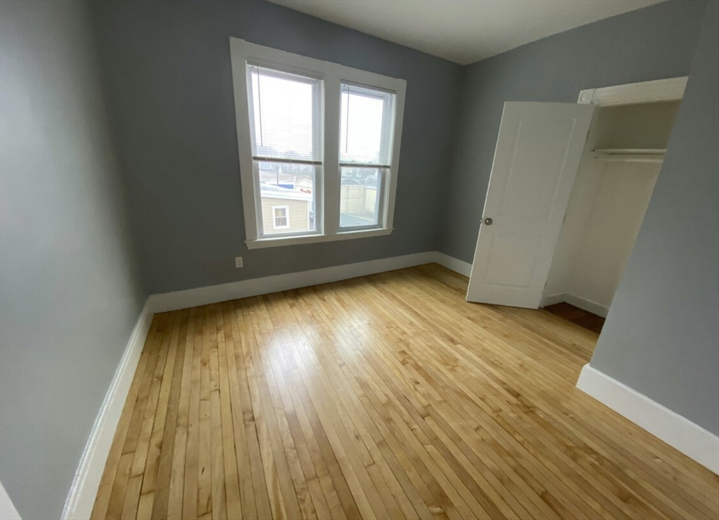 301 Hancock Street, Unit 2 Boston, MA 02125 - Photo 2 of 11 an empty room with wooden floor and windows