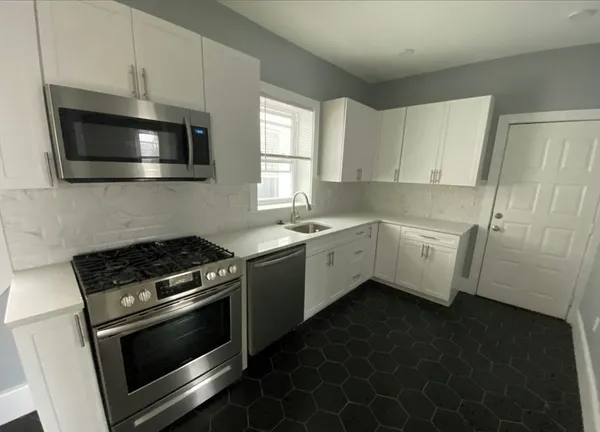 a kitchen with a sink cabinets stainless steel appliances and a window