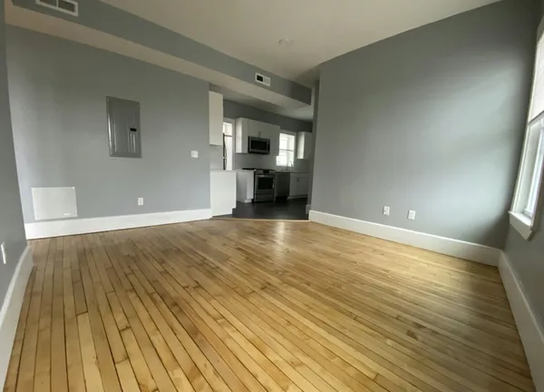 a view of an empty room with wooden floor and a window
