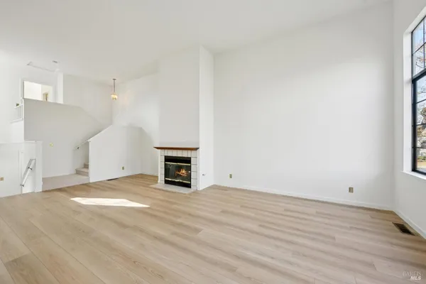 a view of empty room with wooden floor and fireplace