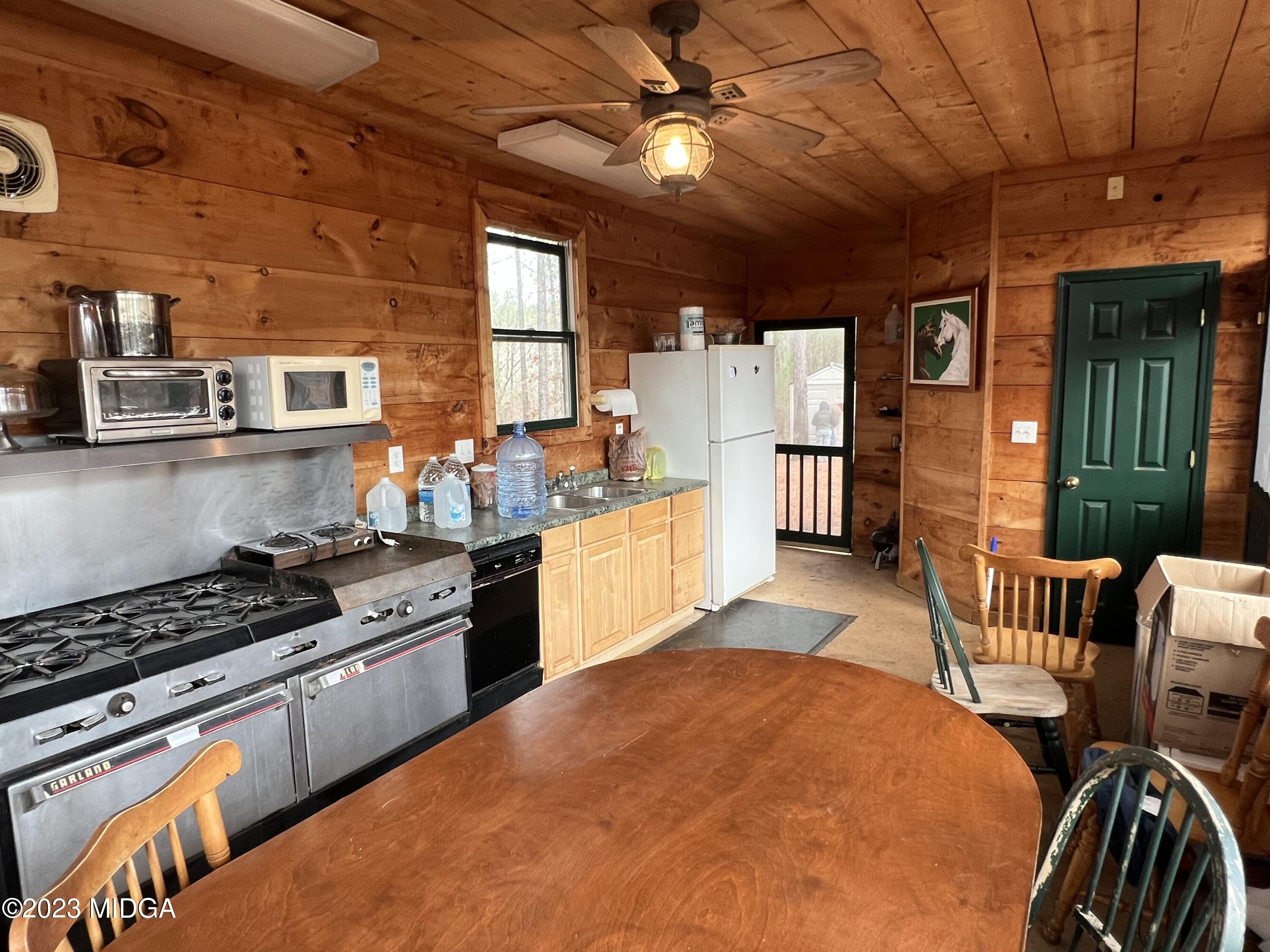 0 Forest Service Road Monticello, GA 31064 - Photo 28 of 32 a kitchen with stainless steel appliances granite countertop a stove top oven a sink a dining table and chairs with wooden floor