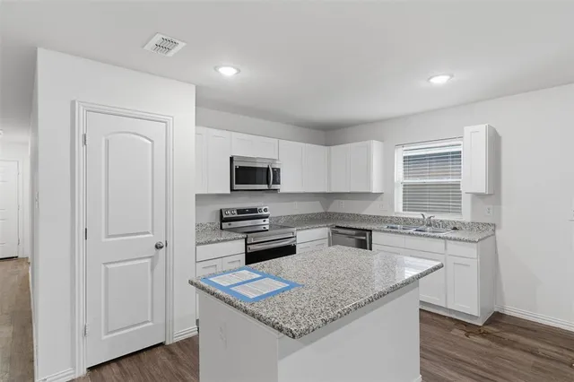 a kitchen with stainless steel appliances granite countertop a stove refrigerator sink and microwave