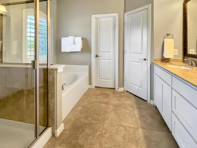 a bathroom with a granite countertop tub sink and mirror