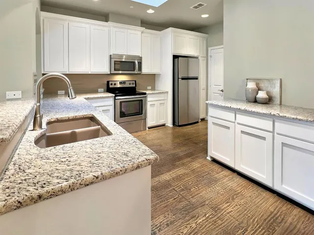 a kitchen with granite countertop a sink a counter space appliances and cabinets