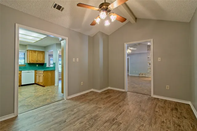 an empty room with windows and chandelier fan