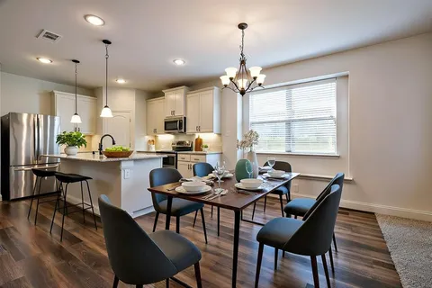 a dining room with stainless steel appliances kitchen island granite countertop a dining table chairs and a refrigerator