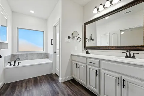 a spacious bathroom with a double vanity sink a mirror and a bathtub
