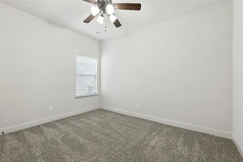 an empty room with a chandelier fan and windows