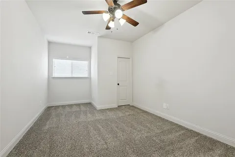an empty room with chandelier fan and windows