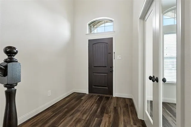 a view of a hallway with wooden floor and front door