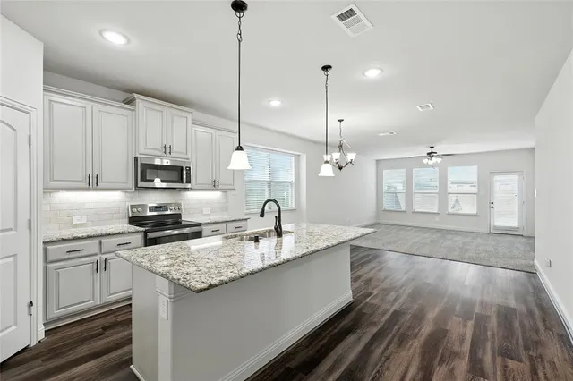 a kitchen with stainless steel appliances granite countertop a sink a stove and oven with wooden floor