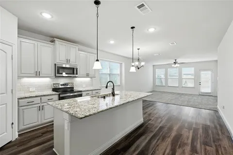 a kitchen with stainless steel appliances granite countertop a sink a stove and oven with wooden floor