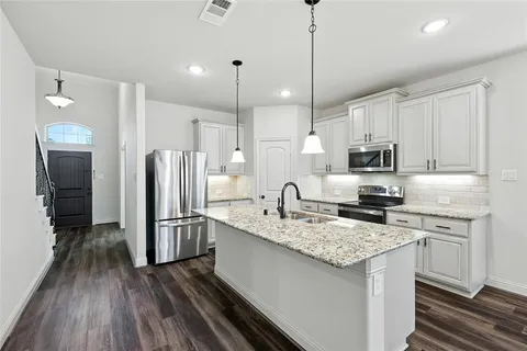 a kitchen with a refrigerator a sink and wooden floor