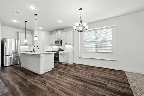 a large white kitchen with kitchen island a sink stainless steel appliances and cabinets