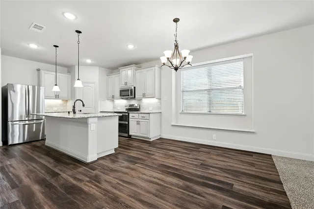 a large white kitchen with kitchen island a sink stainless steel appliances and cabinets