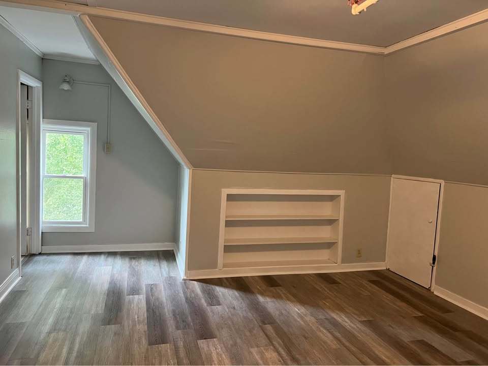 220 College Avenue, Unit 2 DeKalb, IL 60115 - Photo 13 of 14 a view of an empty room with a window and wooden floor
