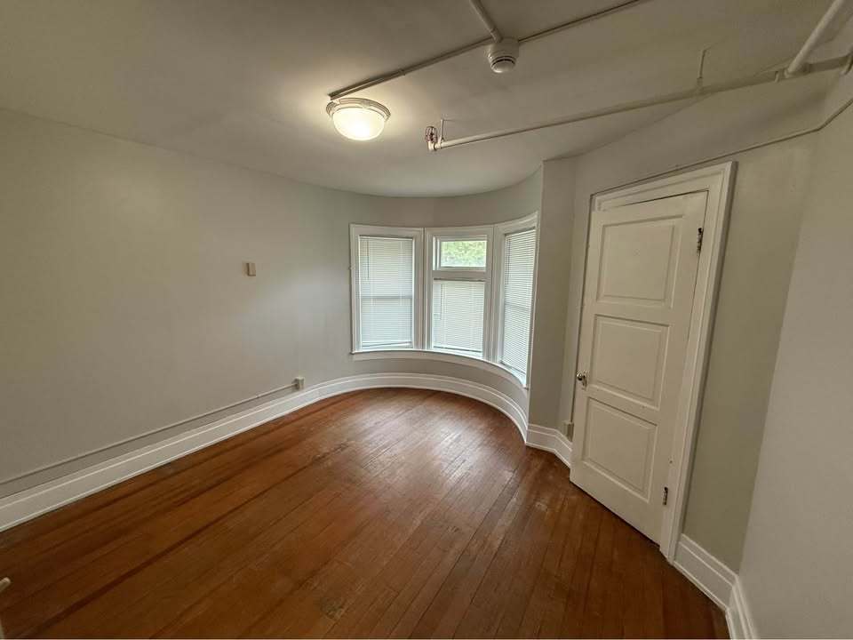 220 College Avenue, Unit 2 DeKalb, IL 60115 - Photo 9 of 14 an empty room with wooden floor and windows