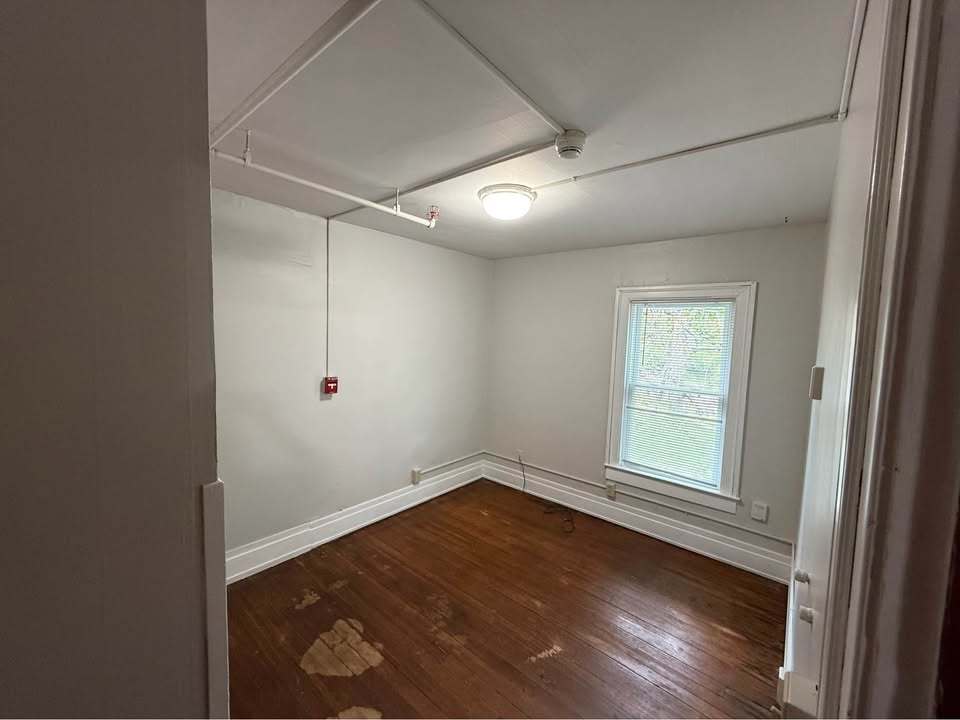 220 College Avenue, Unit 2 DeKalb, IL 60115 - Photo 10 of 14 an empty room with wooden floor and windows