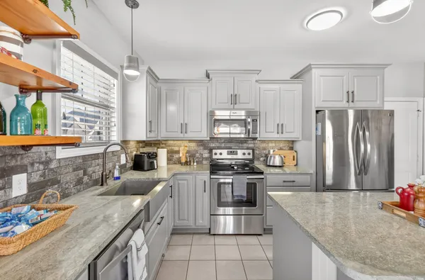 a kitchen with stainless steel appliances granite countertop a sink a stove and a refrigerator