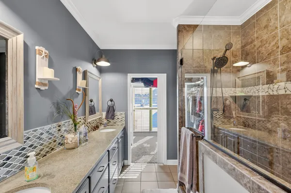 a bathroom with a granite countertop shower a sink and a mirror