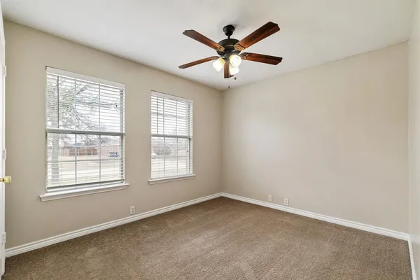 an empty room with ceiling fan and windows