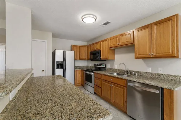 a kitchen with stainless steel appliances granite countertop a sink stove microwave and refrigerator