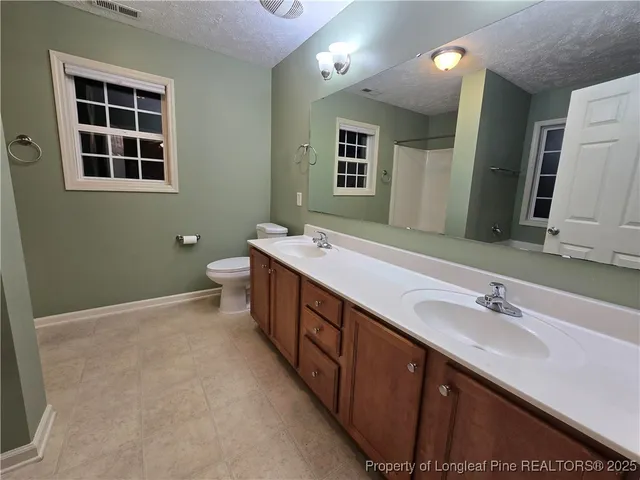 a spacious bathroom with a double vanity sink a large mirror and a