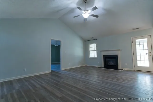 an empty room with wooden floor fireplace and windows