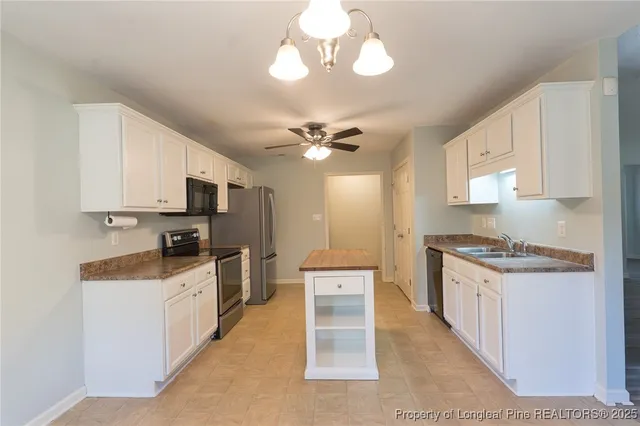 a kitchen with stainless steel appliances a stove top oven a sink a refrigerator cabinets and a dining table