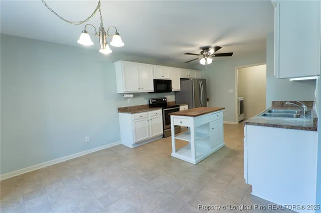 a kitchen with a chandelier stainless steel appliances and cabinets