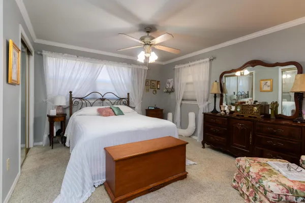 a bedroom with a bed a dresser and a large window